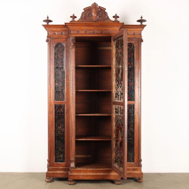 Showcase supported by turned feet, has a broken front with a central door, glass on the sides and sides. In walnut carved...