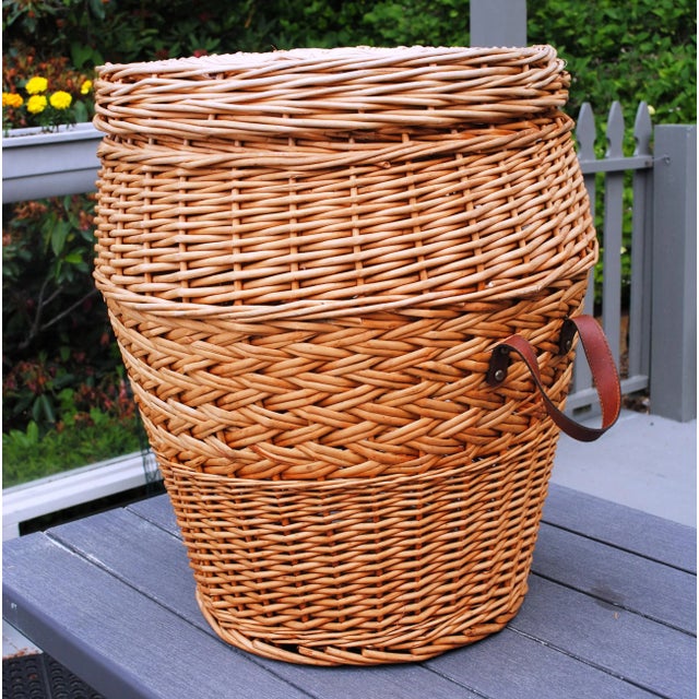 This is a huge wicker basket with leather handles and a lid. It has a wonderful criss-cross design in the middle of the...