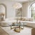 A sophisticated late 20th-century coffee table featuring a heavy, clear glass top supported by a sculptural brass-toned...