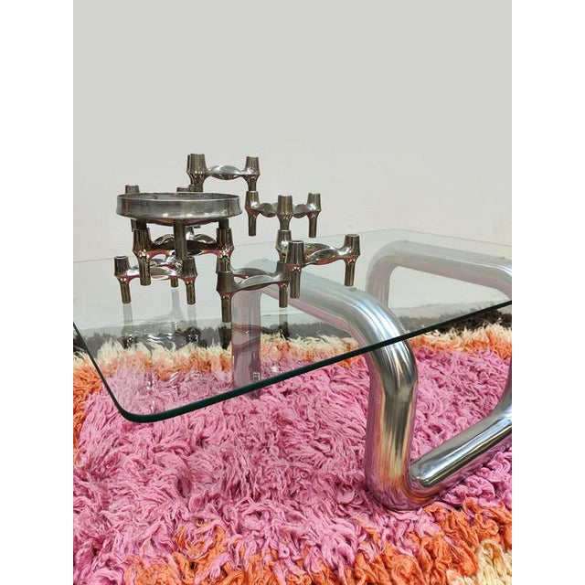 This unique vintage Italian coffee table from the 1980s features a clear glass top with a sculptural, polished metal...