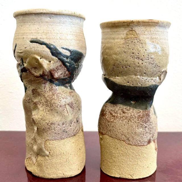 These two hand-thrown ceramic vessels embrace the beauty of imperfection with their raw textures, undulating forms, and...