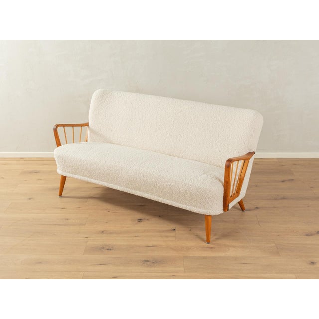Charming sofa from the 1950s. High-quality frame with curved armrests and beechwood legs. The original spring core has...