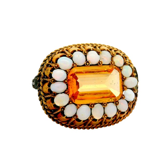 An ornate brooch featuring an approximately 6.00-carat emerald-cut citrine, radiating a vibrant orange hue. Encircled by...