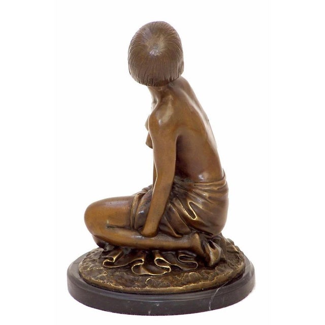 This 20th century Art Deco bronze sculpture in brown patinated bronze represents a seated female nude figure, modeled with...