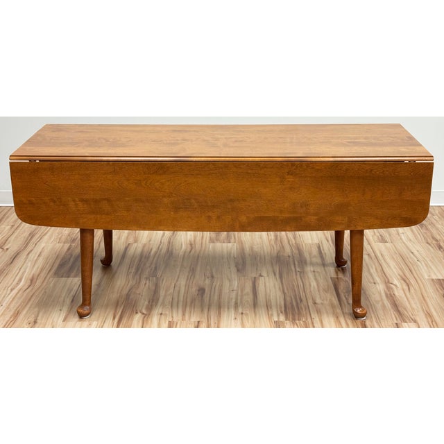 Vintage Ethan Allen natural maple wood drop leaf dining table featuring two rounded edge narrow attached leaves and four...