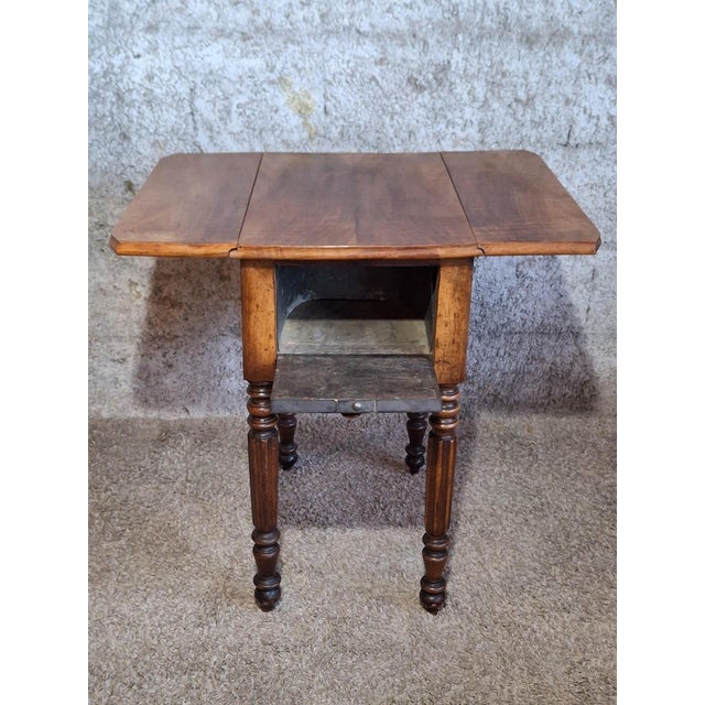 A charming drop-leaf work or sewing table in solid walnut, likely dating from the mid-19th century, in the tradition of...