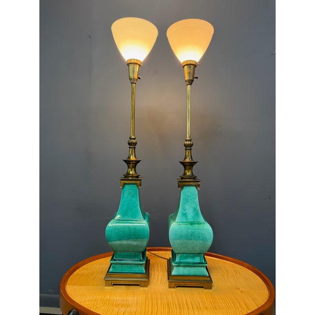 A striking pair of ceramic and brass table lamps designed by Edwin Cole for Stiffel, featuring bold turquoise glazed...