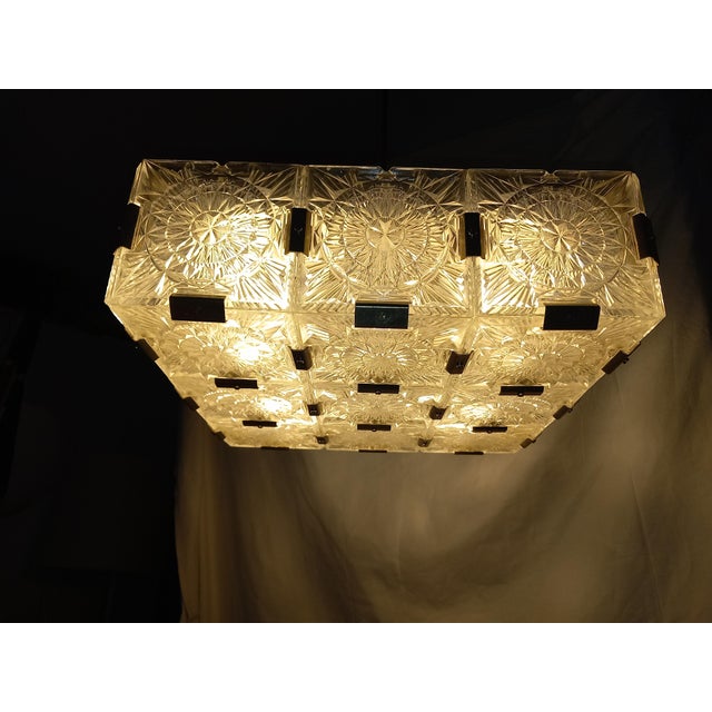 This chandelier is a mid-century design by Kamenicky Senov from the 1970s. The light fixture consists of square glass...