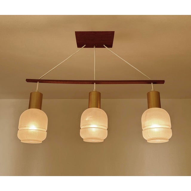 Mid Century Danish modern pendant light featuring a teak wood suspension and 3 opaline glass shades Dimensions: Height 58...