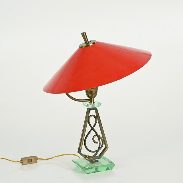 Striking and unique mid-century adjustable table lamp in a refined combination of solid brass, nile green crystal, and red...
