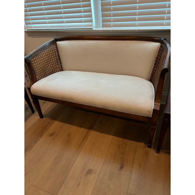 Elegant vintage two-seat settee featuring a warm dark wood frame, gracefully curved arms and upper rail, and beautifully...