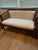 Elegant vintage two-seat settee featuring a warm dark wood frame, gracefully curved arms and upper rail, and beautifully...