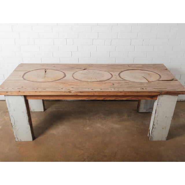 A distinctive rustic farmhouse dining table featuring a solid reclaimed wood top with three striking tree slice inlays....