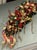 This is a red and gold holiday swag featuring poinsettias, ribbons, and a gold-colored cherub or angel figure. The...