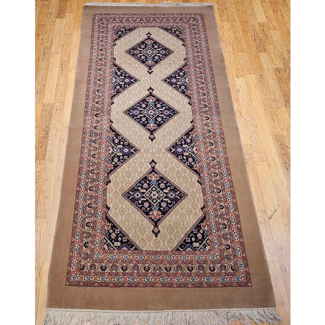 "This exceptional Malayer rug features a striking open-field design set against a warm and inviting camel hair background...