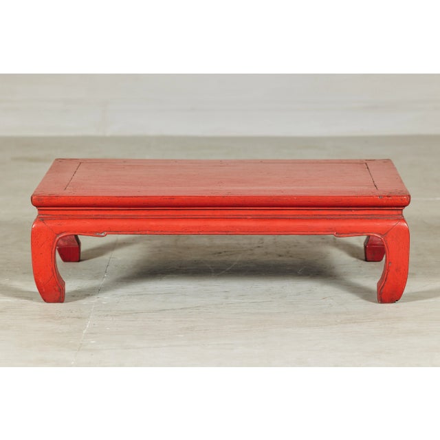 A vintage Chinese low table featuring a red lacquer finish and shaped apron, dating to the 20th century, ideal as a coffee...