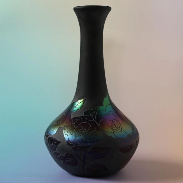 A striking early 20th-century art glass vase in deeply saturated black-amethyst glass, appearing nearly black under...