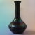 A striking early 20th-century art glass vase in deeply saturated black-amethyst glass, appearing nearly black under...
