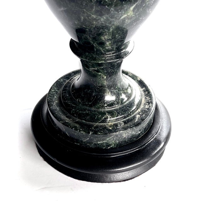 each shapely lamp of well-figured verde antico marble featuring an everted neck above an ovoid body resting on a splayed...