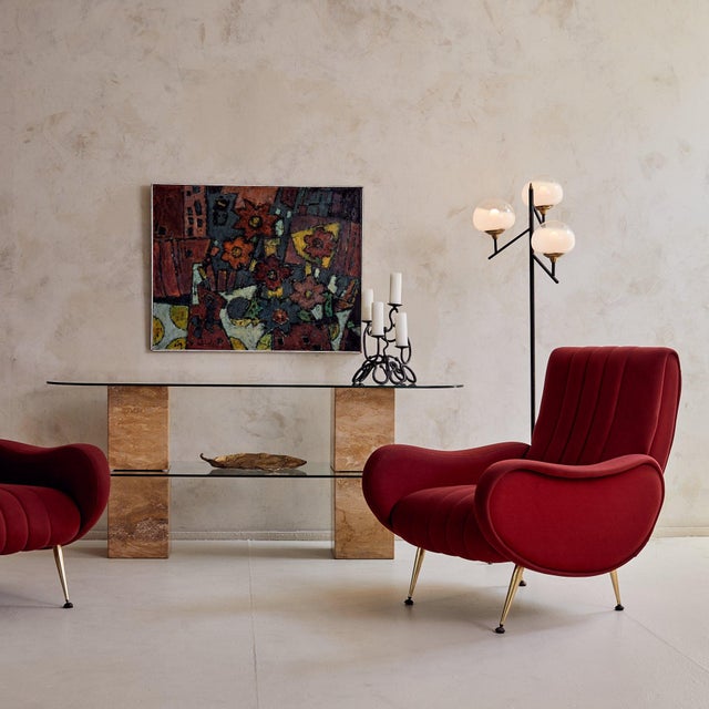 An Italian console table from the 1970s, anchored by four solid travertine pedestals. The organic variation in the stone,...