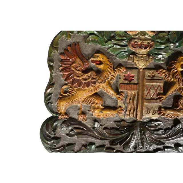 European Painted Wood Coat of Arms Featuring a pair of winged griffons flanking a coat of arms with helmet.