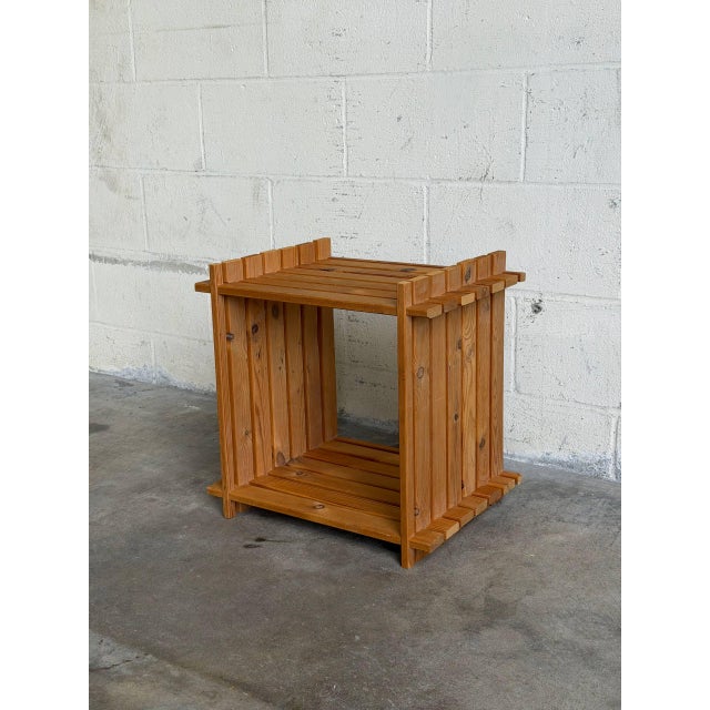 A padded rectangular cushion rests atop four tapered wooden legs. Geometric stitched details accent the top surface. This...