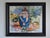 This painting depicts a figure seated in a moment of introspection, with their head bowed and arms wrapped around their...