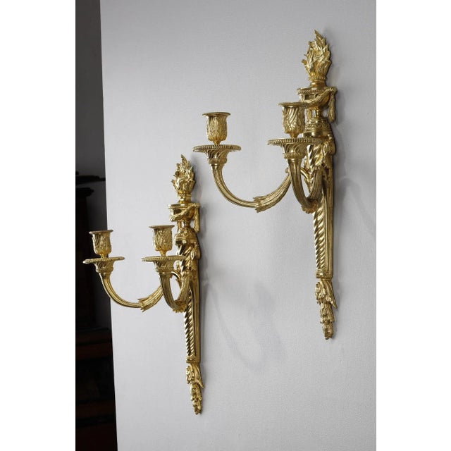 A pair of ormolu and chased sconces with two light arms. The twisted plate is decorated with foliage and volutes. It is...