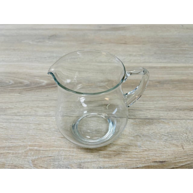 Vintage 1950s handblown clear glass handled pitcher. The handle has a square design. No marks.