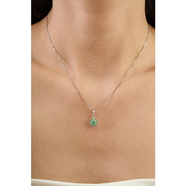 A delicate botanical floral charm pendant featuring 0.58 carats of round emeralds arranged in a graceful cluster design....