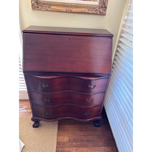 Slant front desk featuring three serpentine drawers with original brass pulls and ball and claw feet. Desk interior...