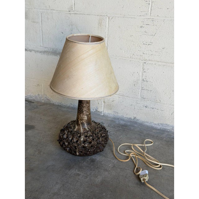 This charming ceramic table lamp features a textured brown base and tapered shade. The warm silhouette brings cozy...