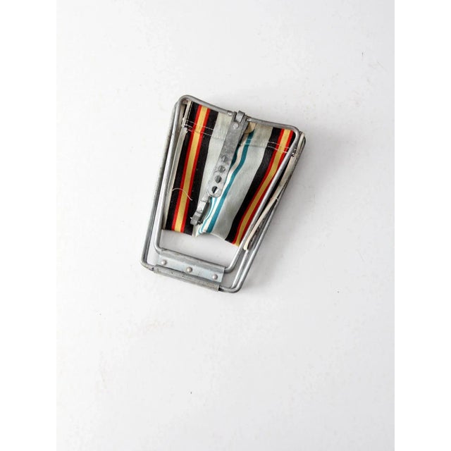 A vintage camp stool. The small folding stool features a metal frame and striped canvas seat. The seat level and tension...