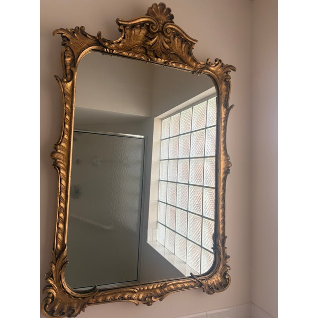 Stunning oversized wall mirror featuring an ornate Rococo Revival frame with elaborate acanthus leaf carvings, shell...