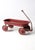 This antique red metal wagon features a shallow ribbed tray, pressed steel wheels, and a classic pull handle. Its timeworn...