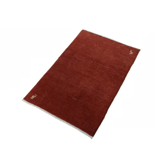 This small, hand-knotted Gabbeh Loribaft rug impresses with its intense, warm red color and the typical minimalist nomadic...