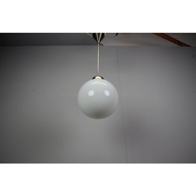A refined Art Deco glass globe pendant chandelier dating from the 1930s, crafted with a spherical glass shade and...