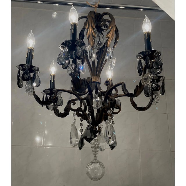 French wrought iron and crystal six arm chandelier. Gold over black cage style frame taking on the form of a hot air...