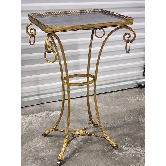 Antique late 19th century French Gueridon table with gray marble top and gilt bronze gallery. The table features a...
