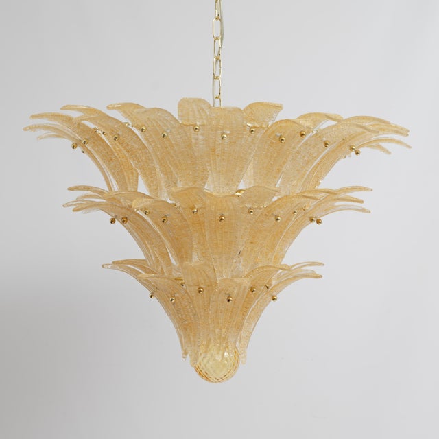 Chandelier crafted from murano glass elements known as palmettes, crafted from transparent glass with honey-colored golden...