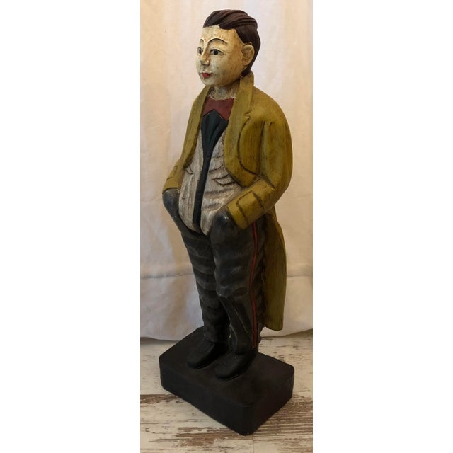 Large and rare solid wood sculpture of a gentleman in a relaxed pose. This gentleman from the early to mid-20th century is...