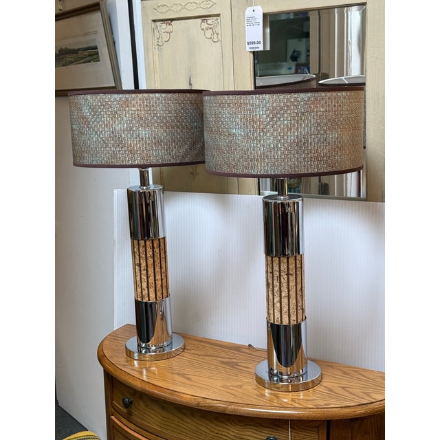 Design Plus Gallery presents a Pair of Chrome Cork Table Lamps. The lamps have a chrome base with cylindrical stem that is...