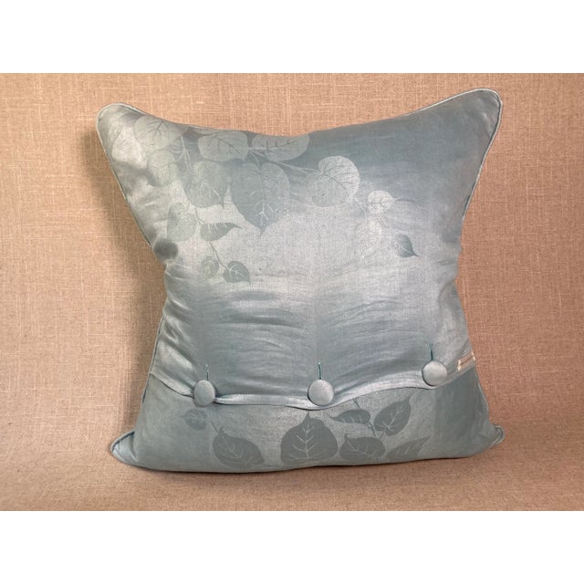 A pillow made from a woven green and cream silk and linen fabric, edged and backed with hand-dyed linen damask. A down...