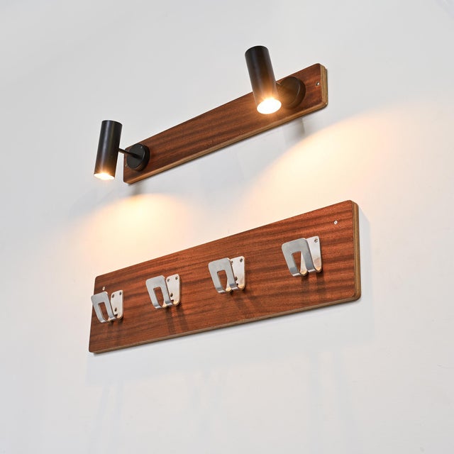 Wall-mounted coat rack composed of a mahogany-veneered plywood panel, to which four aluminum hooks are attached. This...