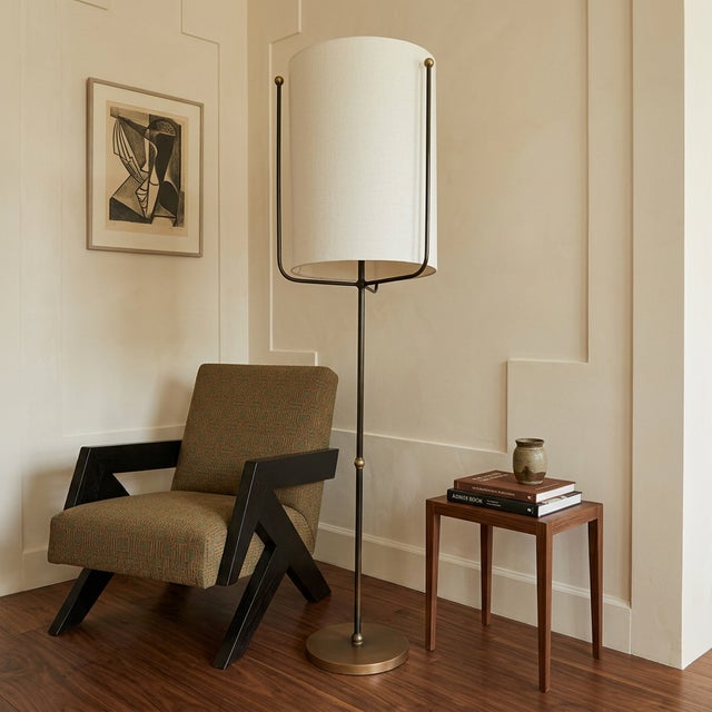 Contemporary Boise floor lamp by Arteriors featuring a slender bronze iron frame anchored by a substantial antique brass...