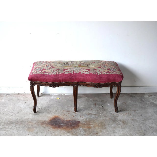 A needlepoint tapestry bench featuring a fox going after grapes and a dog, in the style of Aesop's fables. Carved wood...