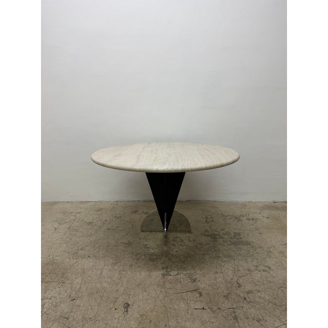 Arrowhead dining table with round natural 1.25” thick travertine top on a black lacquered steel and polished steel base by...
