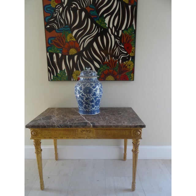 Scaled to impress this neoclassical console has a dark stone top with hand carved gold gilded base. The quality of the...