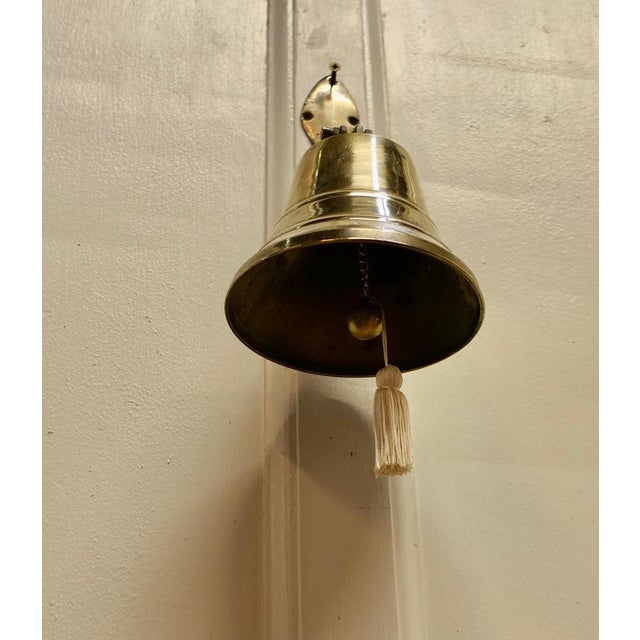 Wall hanging brass door bell. This bell is on a hinged brass bracket and comes complete with hand clapper, it is in very...