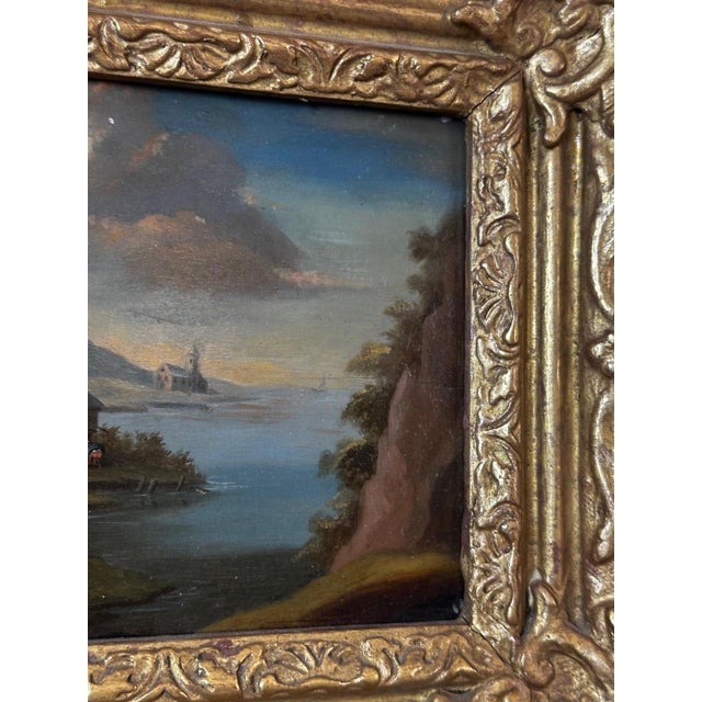 A charming 18th-century Dutch painting, oil on wood panel, depicting a lively village scene by the water in a mountainous...